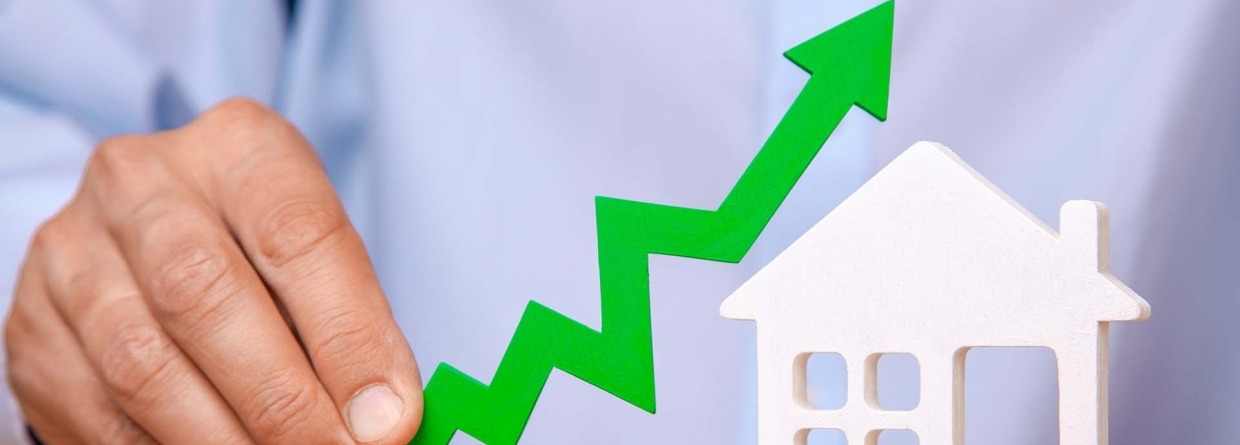Stijgende huizenprijzen, man houdt een groene stijgende pijl in zijn hand naast een icoontje van een huis